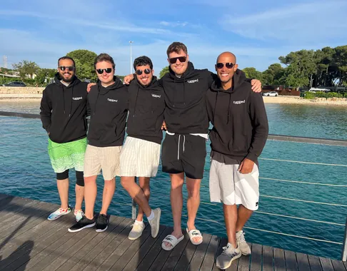 The Tapped team standing together by the water, wearing company hoodies